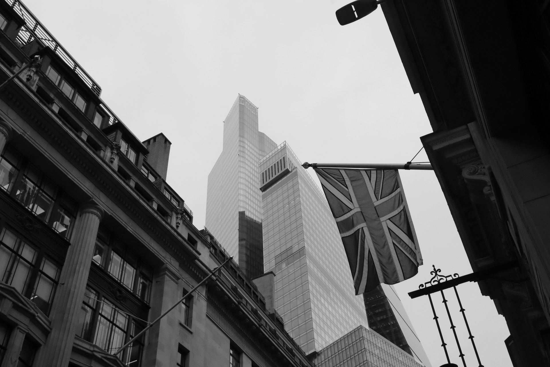 A Union flag between stone buildings and towers in the City of London